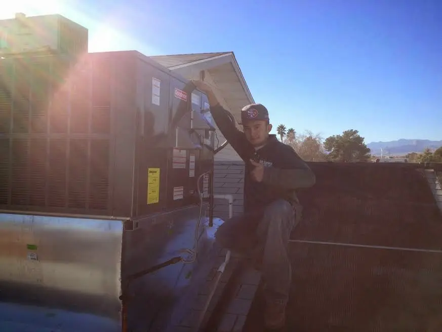 HVAC technician performing Air Duct Cleaning on a rooftop unit in Hooper